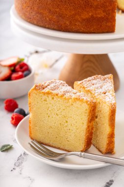 Klasik vanilyalı kek dilimlenmiş ve taze dutlarla servis edilmeye hazır.