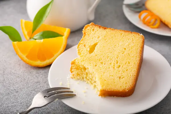 Orange pound cake slice on a plate ready to eat, bundt cake topped with powdered sugar