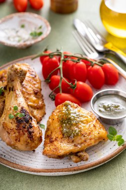 Pesto ve domatesle servis edilen kızarmış tavuk budu ve but.