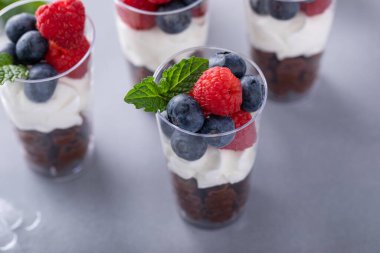 Krem şantili çikolatalı mus fincanları ve ayrı bardaklarda servis edilen taze meyveler.