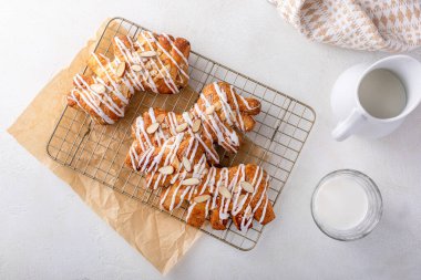 Bear claws pastry drizzled with sugar glaze and topped with almond slices clipart