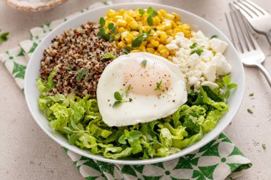 Besleyici kinoa kahvaltı kasesi üzerine sahanda yumurta ve bir fincan kahveyle servis edilen tatlı mısır.