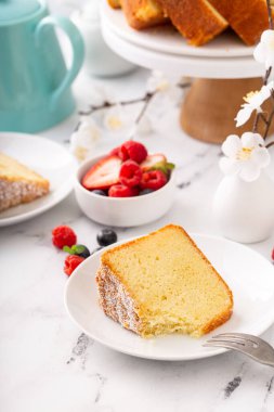 Klasik vanilyalı kek dilimlenmiş ve taze dutlarla servis edilmeye hazır.