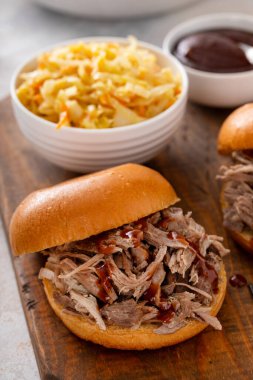 Brioche çörekleri üzerinde domuz sandviçi, barbekü sosu ve sotelenmiş lahana.