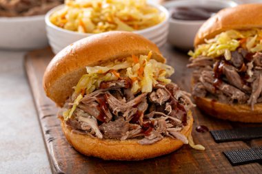 Brioche çörekleri üzerinde domuz sandviçi, barbekü sosu ve sotelenmiş lahana.