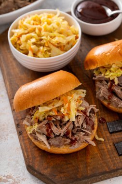 Brioche çörekleri üzerinde domuz sandviçi, barbekü sosu ve sotelenmiş lahana.