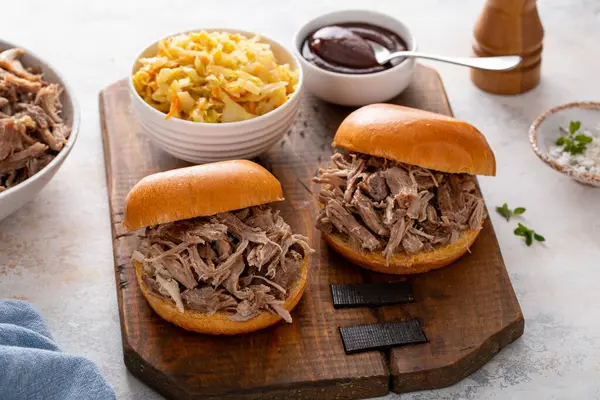 Brioche çörekleri üzerinde domuz sandviçi, barbekü sosu ve sotelenmiş lahana.