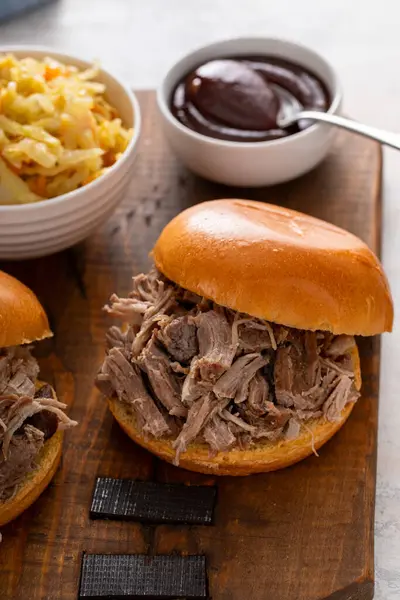 Brioche çörekleri üzerinde domuz sandviçi, barbekü sosu ve sotelenmiş lahana.