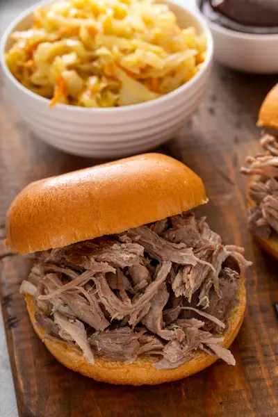 Brioche çörekleri üzerinde domuz sandviçi, barbekü sosu ve sotelenmiş lahana.