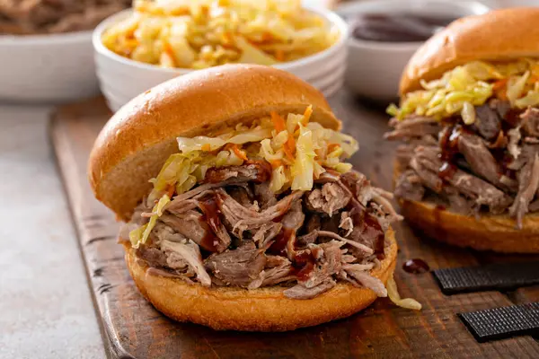 Brioche çörekleri üzerinde domuz sandviçi, barbekü sosu ve sotelenmiş lahana.