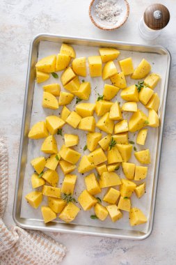 Çiğ patates, sarımsak, bitki ve baharatla kızartılmaya hazır bir tavada dilimlenmiş.