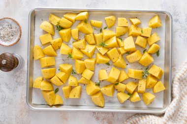 Çiğ patates, sarımsak, bitki ve baharatla kızartılmaya hazır bir tavada dilimlenmiş.