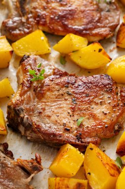 Kolay bir akşam yemeği için baharatlı ve otlu bir tavada kızartılmış domuz pirzolası ve patates.