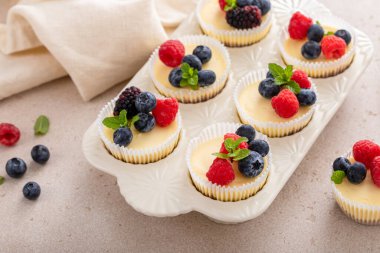 Taze böğürtlenlerle kaplı kek tavasında pişirilmiş mini peynirli kekler. Tatlı bir fikir.