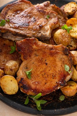 Kızarmış veya sotelenmiş domuz pirzolası servis tabağında kızarmış patatesle servis edilir.