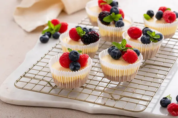 Taze böğürtlenlerle kaplı kek tavasında pişirilmiş mini peynirli kekler. Tatlı bir fikir.