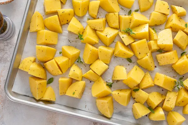 Çiğ patates, sarımsak, bitki ve baharatla kızartılmaya hazır bir tavada dilimlenmiş.