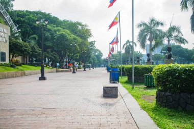 Rizal Park, Manila, Filipinler 2 Temmuz 2014: Taft Bulvarı, Manila, Filipinler yakınlarındaki Rizal Park 'ta bir sıra Filipin bayraklı ve ağaçlı patika