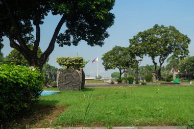 Rizal Park, Manila, Filipinler 2 Temmuz 2014: Filipin Bayrağı Manila, Filipinler 'deki Rizal Park' ta çimenler ve ağaçlar tarafından çerçevelendi