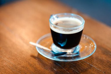 Cup of black coffee on wooden table in coffee shop. Copy space. Indoor.