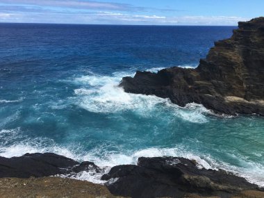 Honolulu Sahili dağları, büyük kayalar, mavi sular ve yüksek dalgalar.