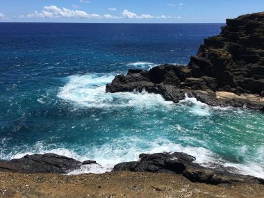Honolulu Sahili dağları, büyük kayalar, mavi sular ve yüksek dalgalar.