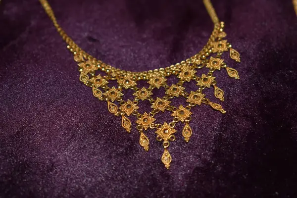 Siyah arka planda altın bir kolye.