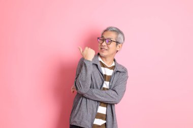 40 'lı yaşlarda Asyalı bir adam pembe arka planda sıradan kıyafetlerle dolanıyor..