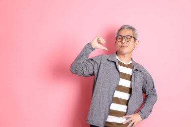 40 'lı yaşlarda Asyalı bir adam pembe arka planda sıradan kıyafetlerle dolanıyor..