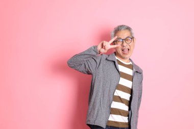 40 'lı yaşlarda Asyalı bir adam pembe arka planda sıradan kıyafetlerle dolanıyor..