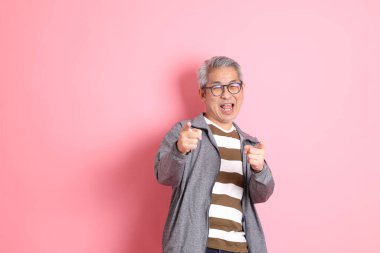 40 'lı yaşlarda Asyalı bir adam pembe arka planda sıradan kıyafetlerle dolanıyor..