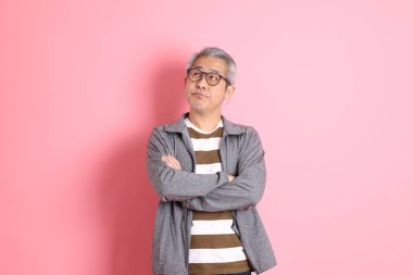 40 'lı yaşlarda Asyalı bir adam pembe arka planda sıradan kıyafetlerle dolanıyor..