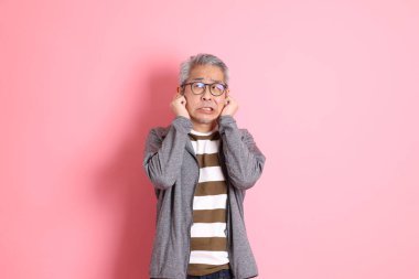 40 'lı yaşlarda Asyalı bir adam pembe arka planda sıradan kıyafetlerle dolanıyor..