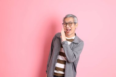 40 'lı yaşlarda Asyalı bir adam pembe arka planda sıradan kıyafetlerle dolanıyor..