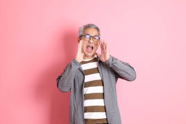 40 'lı yaşlarda Asyalı bir adam pembe arka planda sıradan kıyafetlerle dolanıyor..