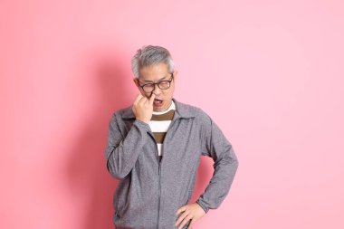 40 'lı yaşlarda Asyalı bir adam pembe arka planda sıradan kıyafetlerle dolanıyor..