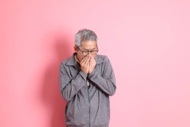 40 'lı yaşlarda Asyalı bir adam pembe arka planda sıradan kıyafetlerle dolanıyor..