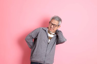 40 'lı yaşlarda Asyalı bir adam pembe arka planda sıradan kıyafetlerle dolanıyor..