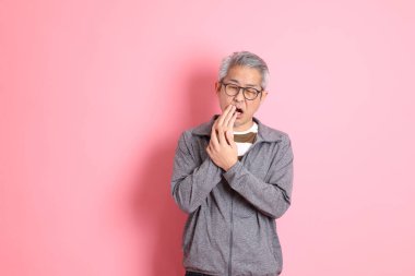 40 'lı yaşlarda Asyalı bir adam pembe arka planda sıradan kıyafetlerle dolanıyor..