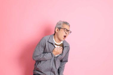 40 'lı yaşlarda Asyalı bir adam pembe arka planda sıradan kıyafetlerle dolanıyor..