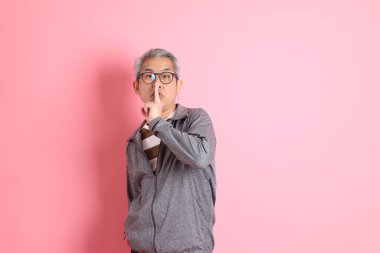 40 'lı yaşlarda Asyalı bir adam pembe arka planda sıradan kıyafetlerle dolanıyor..