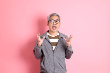 40 'lı yaşlarda Asyalı bir adam pembe arka planda sıradan kıyafetlerle dolanıyor..