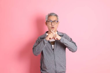 40 'lı yaşlarda Asyalı bir adam pembe arka planda sıradan kıyafetlerle dolanıyor..