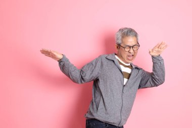 40 'lı yaşlarda Asyalı bir adam pembe arka planda sıradan kıyafetlerle dolanıyor..