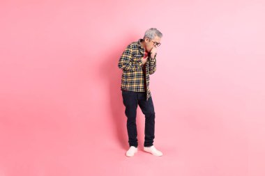 Pembe arka planda duran yaşlı Asyalı adamın boyu....
