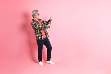 Pembe arka planda duran yaşlı Asyalı adamın boyu....