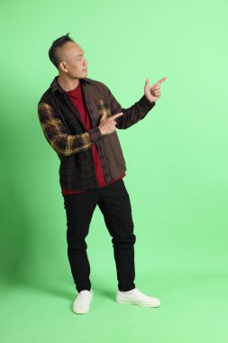 Yeşil arka planda duran ekose gömlekli 40 'lı yaşlardaki Asyalı adam..