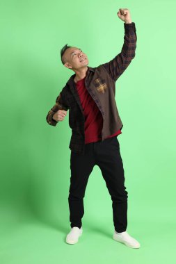 Yeşil arka planda duran ekose gömlekli 40 'lı yaşlardaki Asyalı adam..