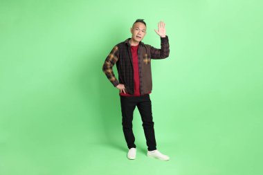 Yeşil arka planda duran ekose gömlekli 40 'lı yaşlardaki Asyalı adam..