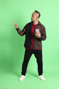 Yeşil arka planda duran ekose gömlekli 40 'lı yaşlardaki Asyalı adam..